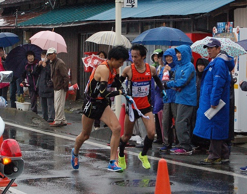 雨の中たすきをつなぐ小山選手と永井選手