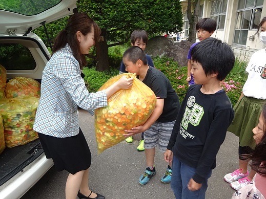 小学生にエコキャップを手渡す弊社社員の様子